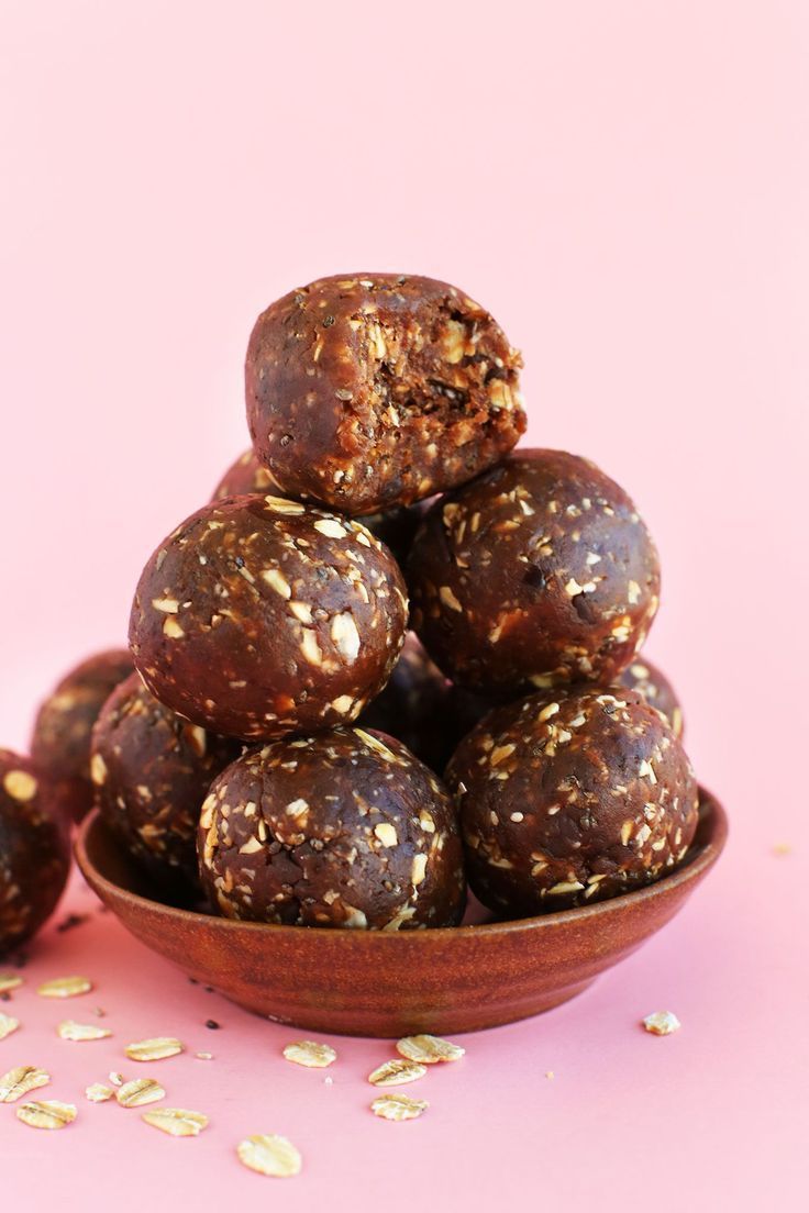 This may contain: a wooden bowl filled with chocolate covered donuts on top of a pink tablecloth