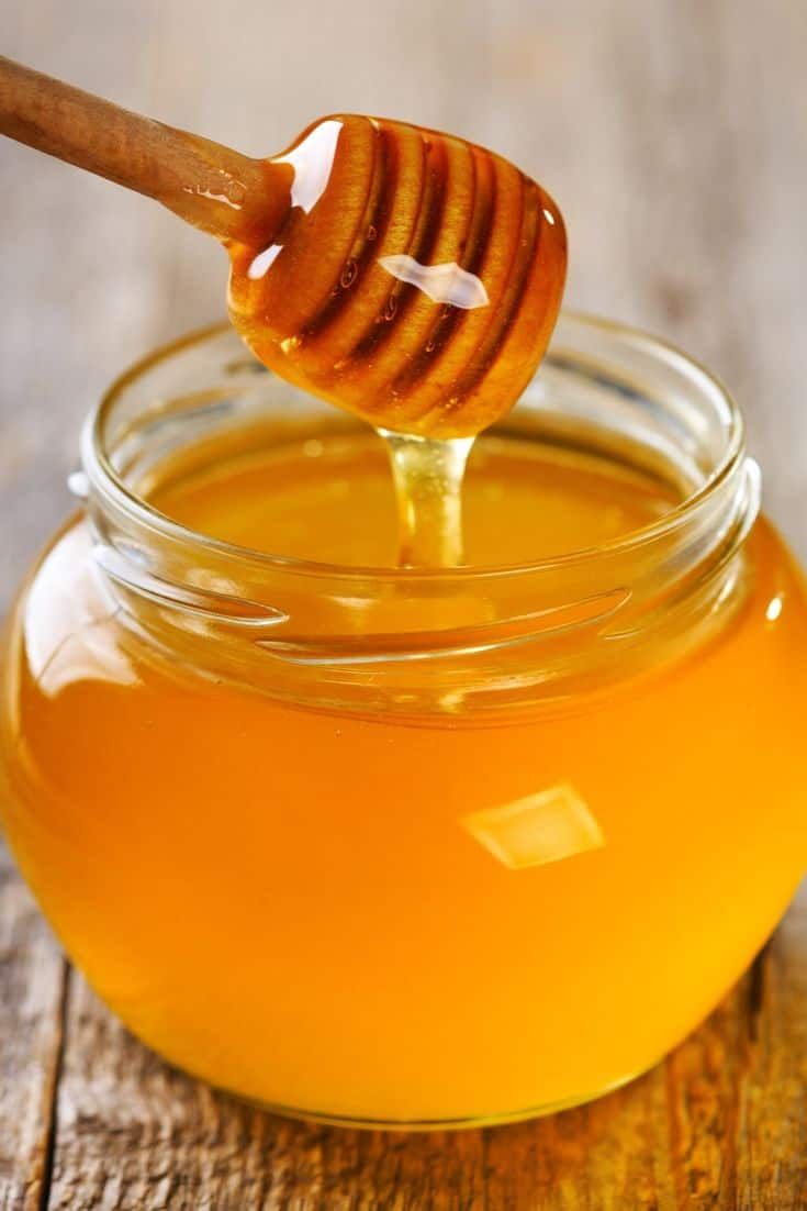 This may contain: a honey jar with a wooden spoon full of honey