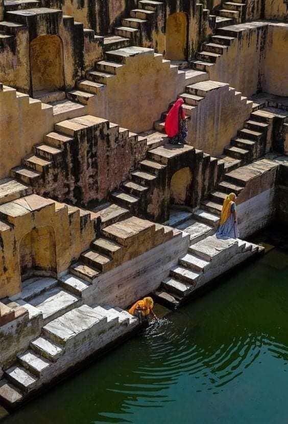 This may contain: two people are standing on the edge of some steps next to a body of water