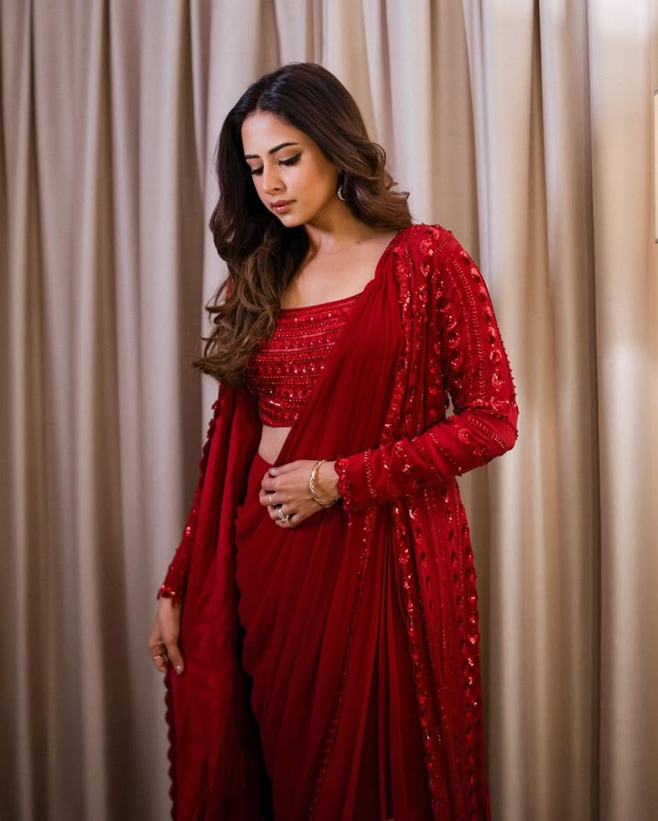 This may contain: a woman in a red sari is posing for the camera with her hands on her hips