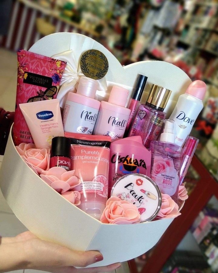 This may contain: a person holding a heart shaped box filled with beauty products