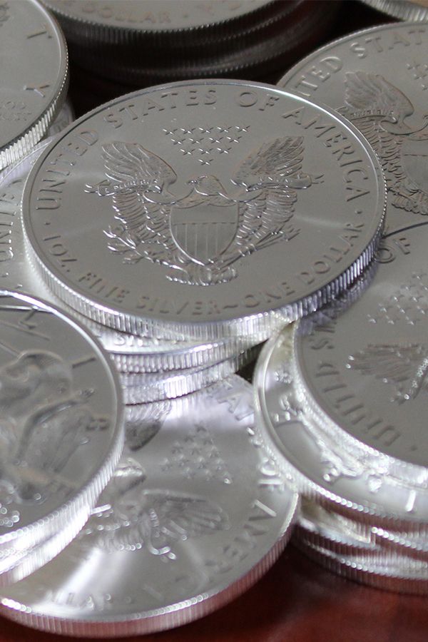 This may contain: a pile of silver coins sitting on top of a wooden table next to each other