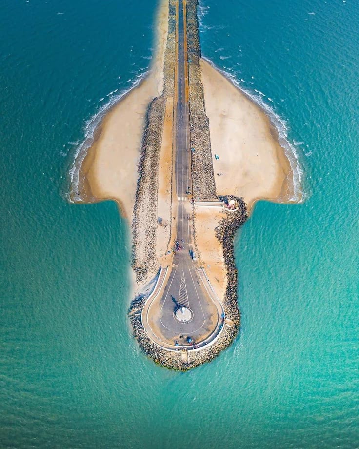 This may contain: an aerial view of a long pier in the middle of the ocean with cars driving on it