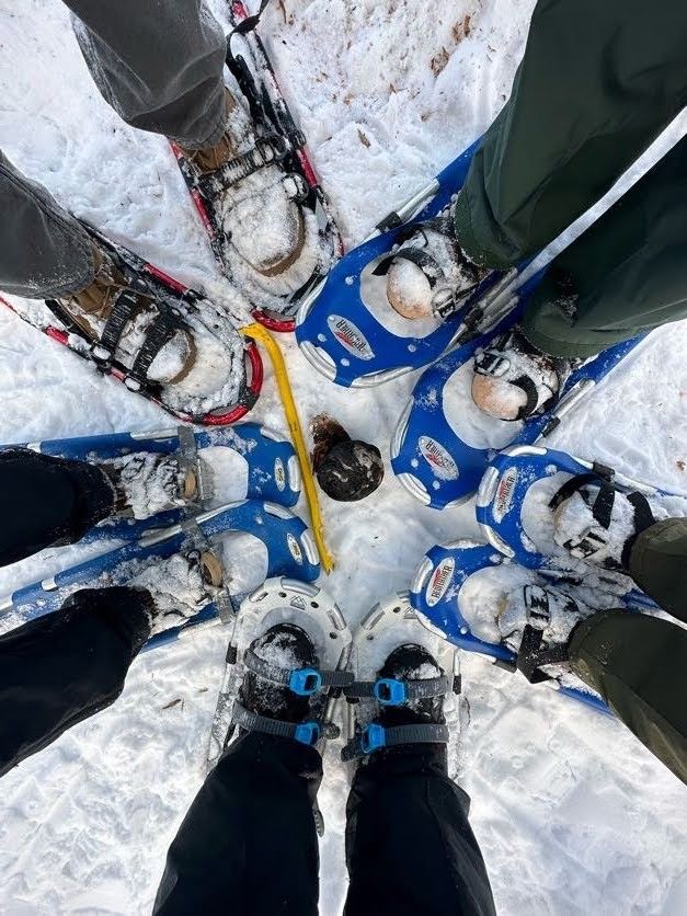 This may contain: four people standing in a circle with their skis on