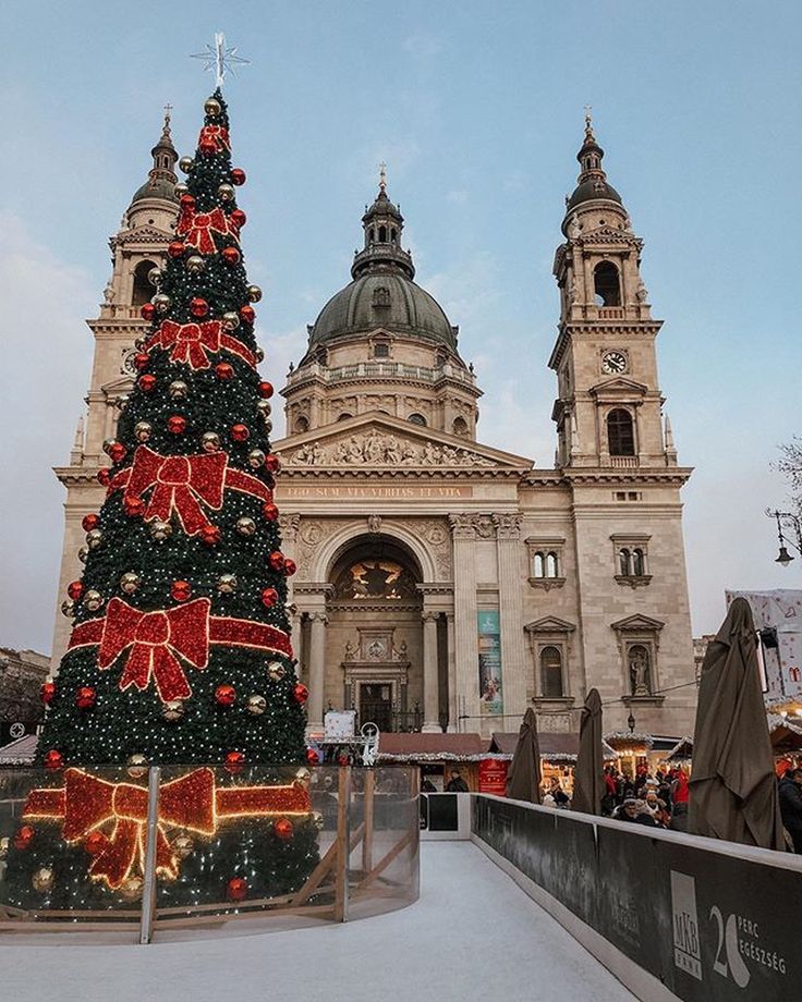 This may contain: a large christmas tree is in front of a building with two towers and lights on it