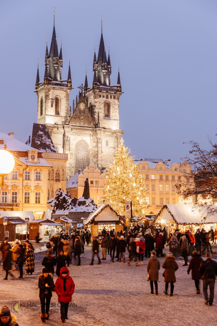 This may contain: people are walking around in front of a christmas tree at the old town square, prague