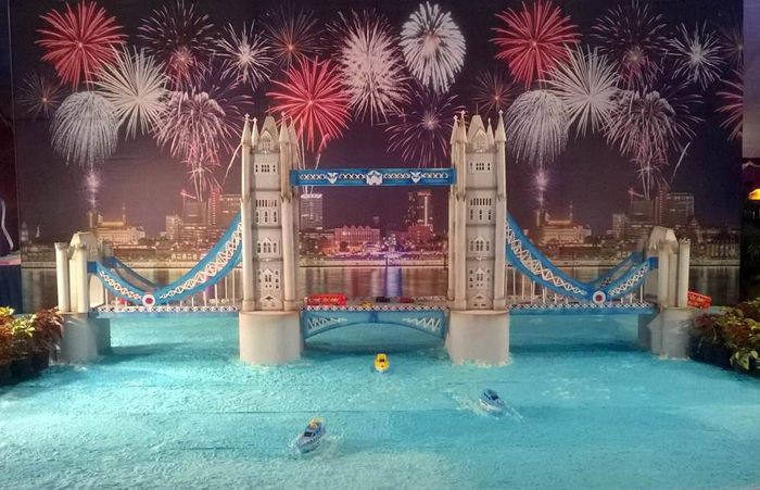 This may contain: fireworks are lit up in the sky above a swimming pool and bridge with people on it