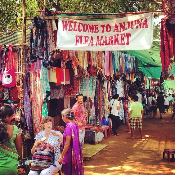 This may contain: an outdoor market with people shopping and selling items on the sidewalk, in front of a sign that reads welcome to aniva flea market