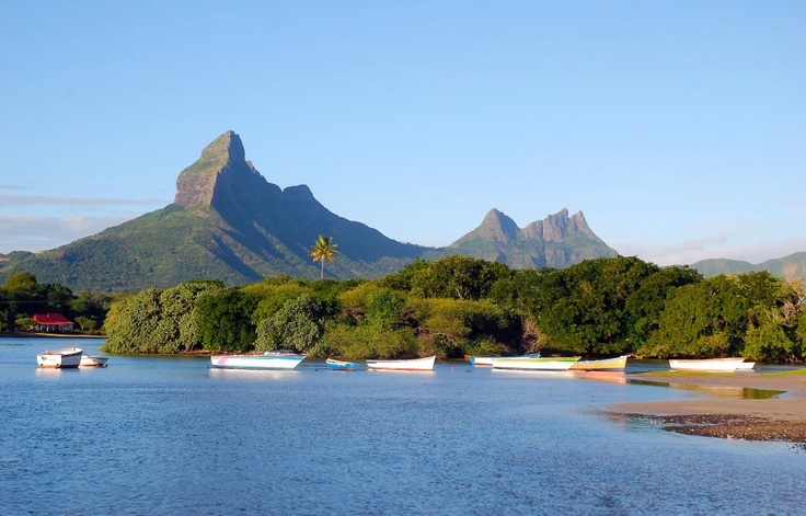 This may contain: there are many small boats in the water near some mountains and trees on the shore