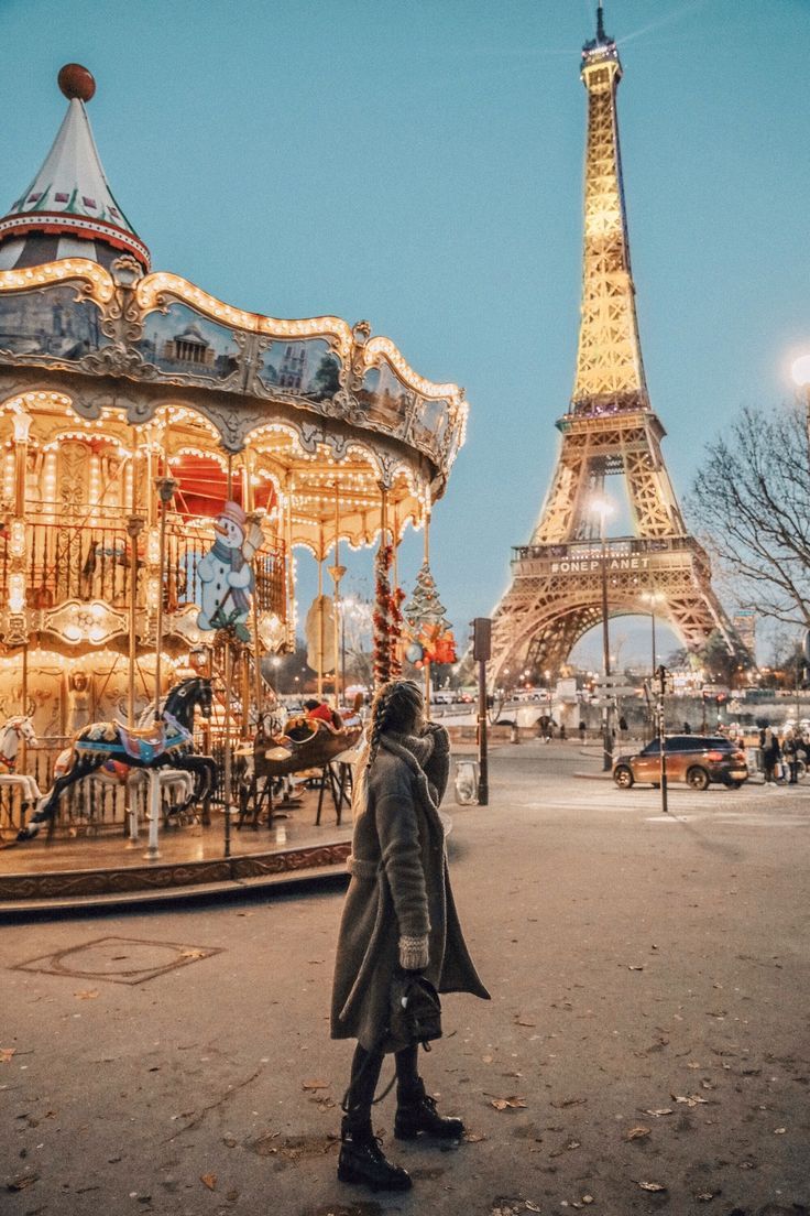 This may contain: a woman standing in front of the eiffel tower