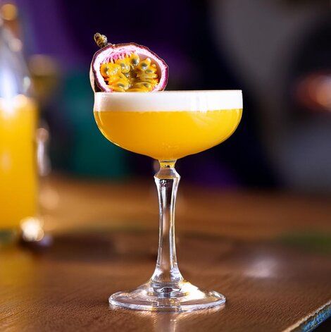 This may contain: a glass filled with an orange drink on top of a wooden table