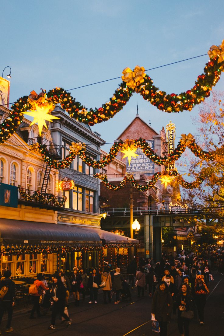 This may contain: people are walking down the street in front of buildings decorated with lights and garlands