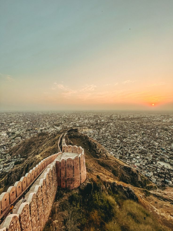 This may contain: an aerial view of the city and its surrounding walls from atop a hill at sunset