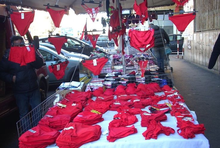 This may contain: red shirts are on display at an outdoor market