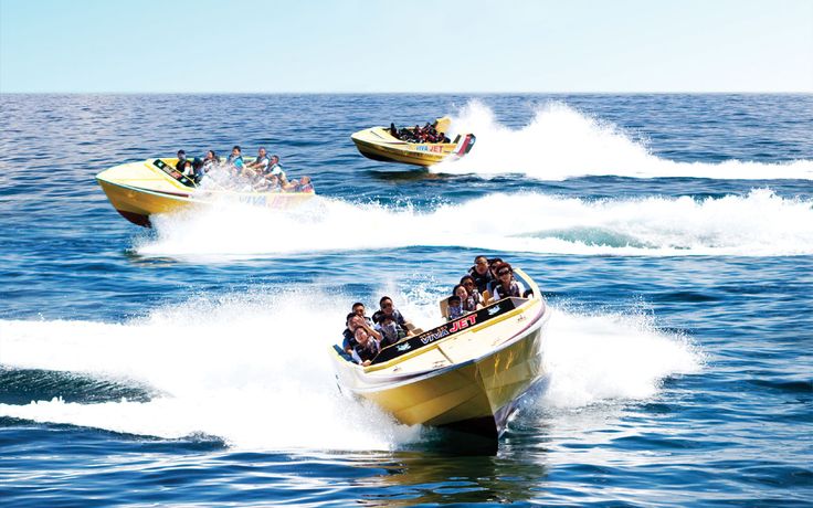 This may contain: four speed boats with people on them in the middle of the ocean, one being pulled by a boat