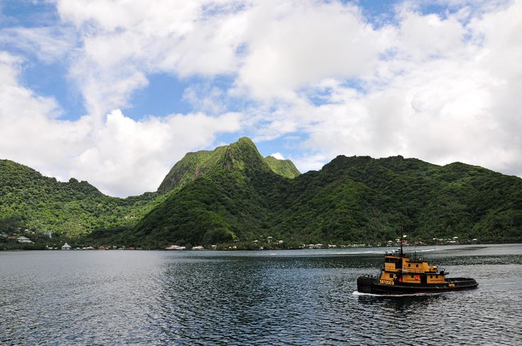 This may contain: a tug boat in the middle of a body of water with mountains in the background