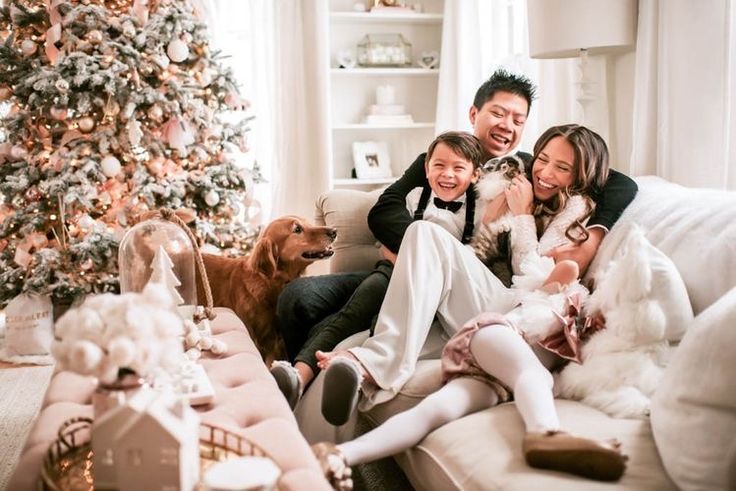 This may contain: a family sitting on a couch in front of a christmas tree