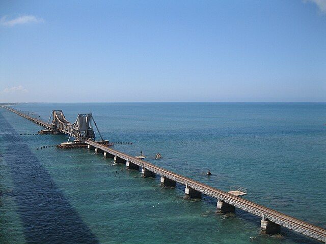 This may contain: a long bridge over the ocean with people on it