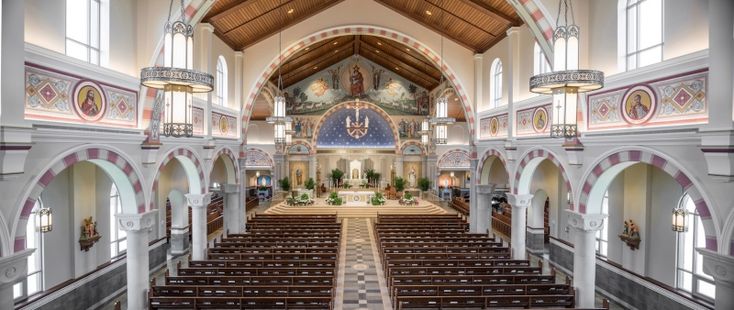 This may contain: the inside of a large church with pews and stained glass windows on both sides