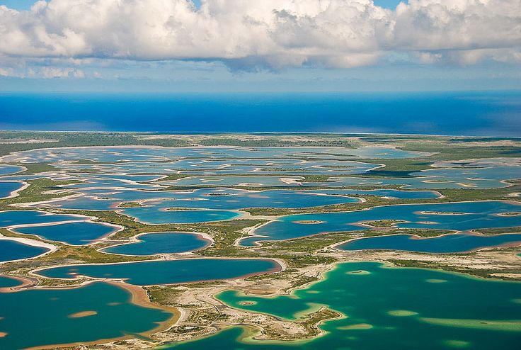 This may contain: an aerial view of the ocean and landforms from above, with clouds in the sky