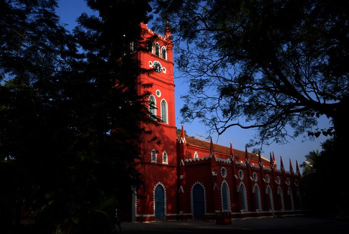 This may contain: a tall red building with a clock on it's side and trees in the foreground