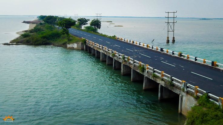 This may contain: an aerial view of a bridge over the ocean with cars driving on one side and water in the other