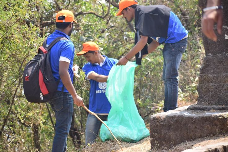This may contain: three men in blue shirts and orange hats are picking up trash