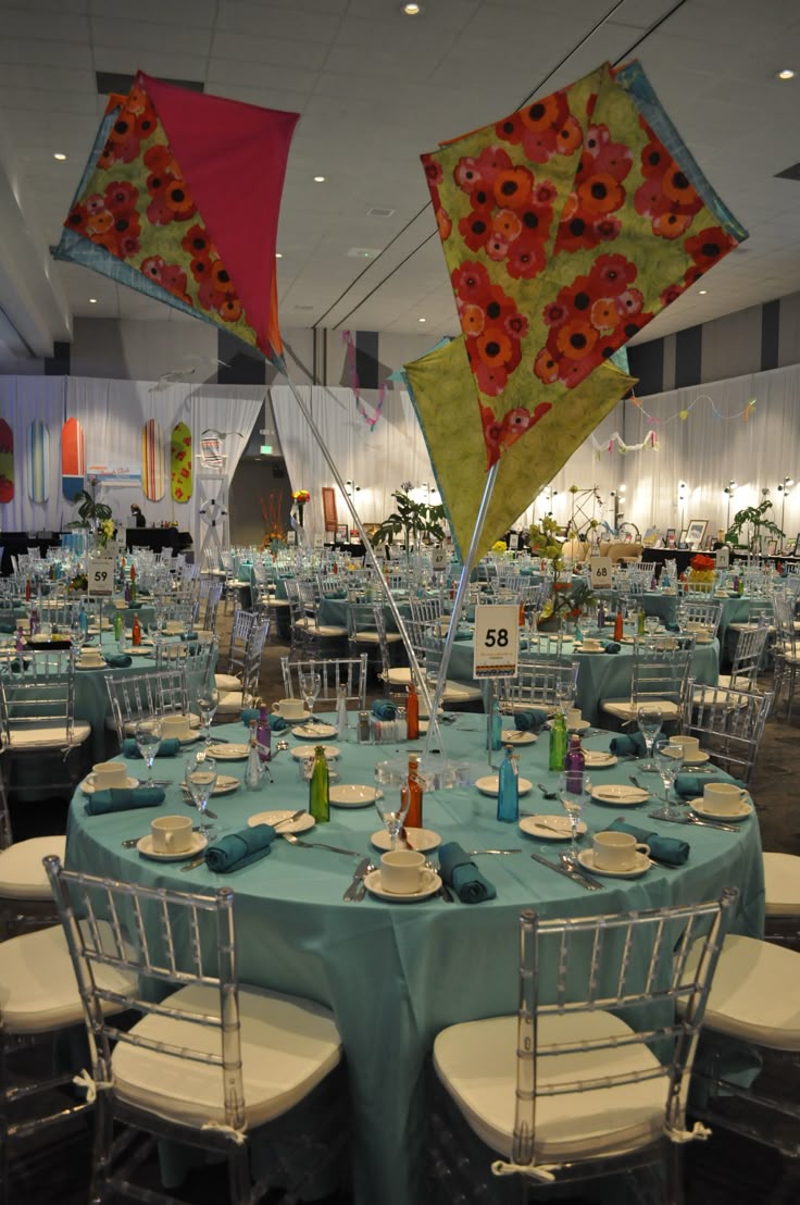 This may contain: an indoor event with tables and chairs set up for a banquet or party, decorated with colorful umbrellas