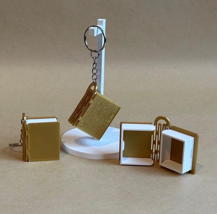 This may contain: three pieces of miniature gold and white items on a table with a keychain