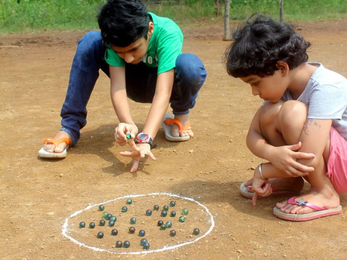 This may contain: two children playing with beads on the ground