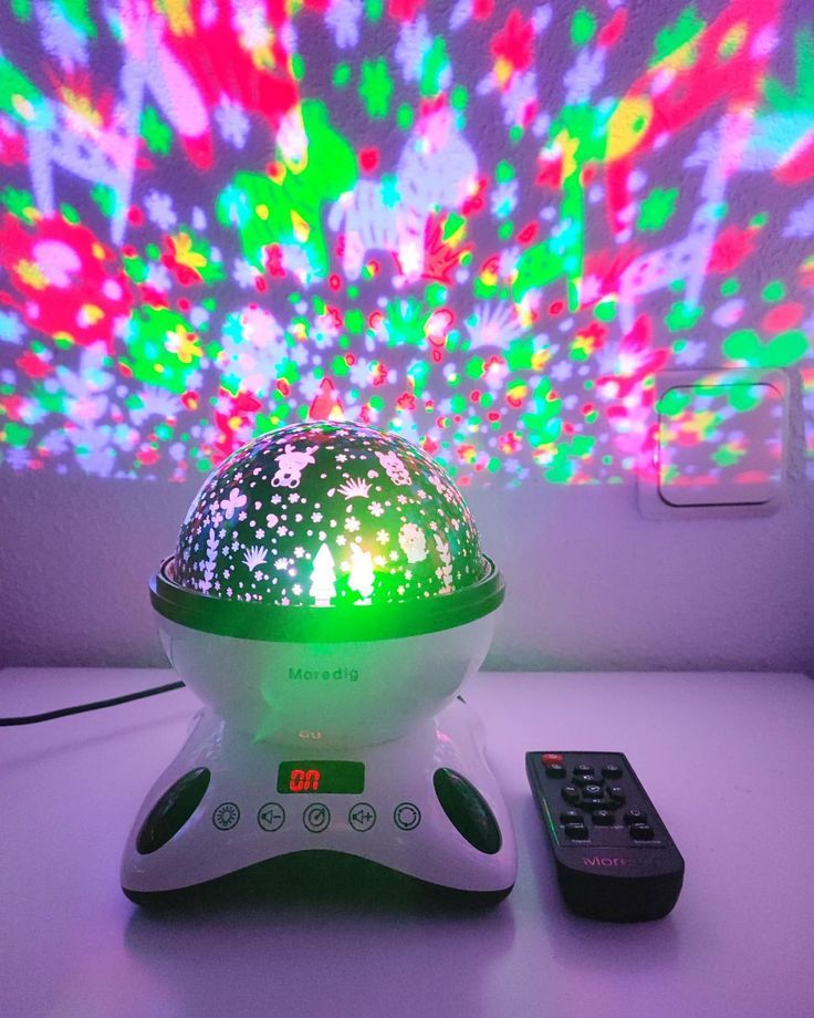 This may contain: a remote control sitting on top of a table next to a colorful light projector