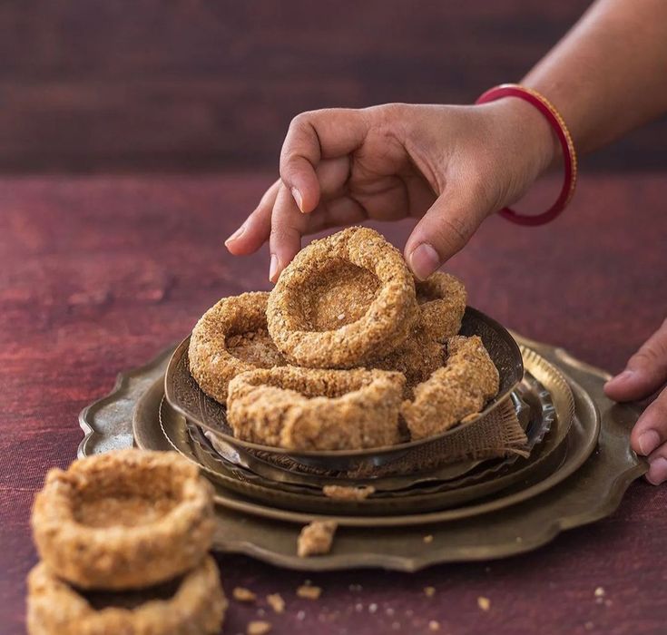 This may contain: a person reaching for some kind of doughnuts on a plate next to other small ones