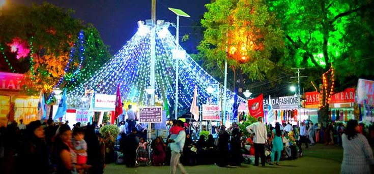 This may contain: a crowd of people standing around a tent covered in lights