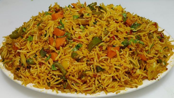 This may contain: a white plate topped with yellow rice and vegetables