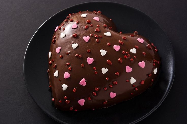 This may contain: a heart shaped chocolate cake on a black plate