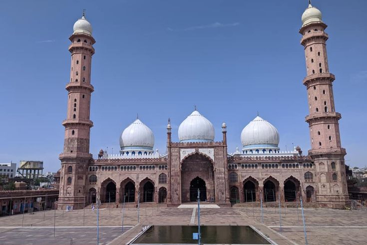 This may contain: an old building with two white domes on it's sides and a fountain in the middle