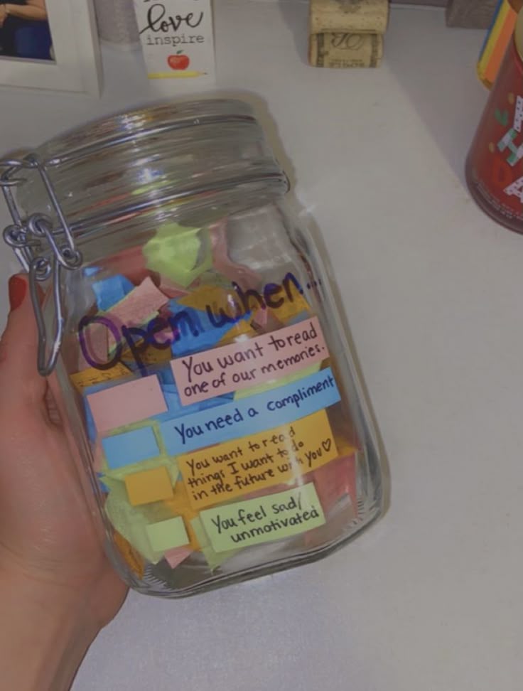This may contain: a person holding a jar with sticky notes on it and magnets attached to the lid