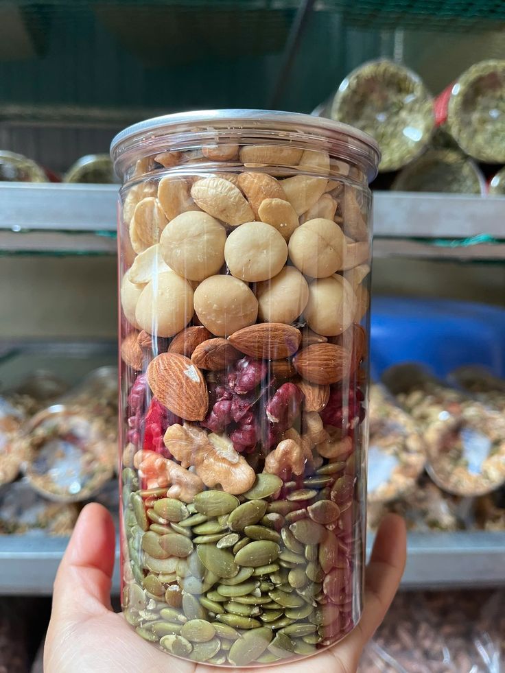 This may contain: a person holding up a jar filled with nuts