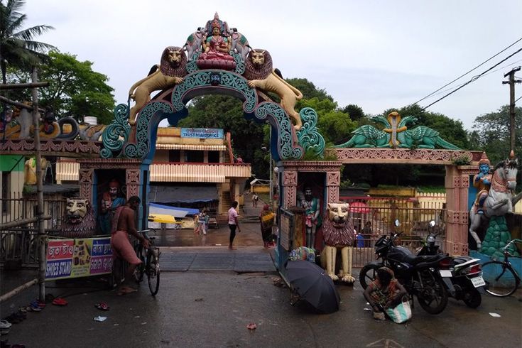 This may contain: a group of people standing in front of a gate with statues on it and motorcycles parked near by