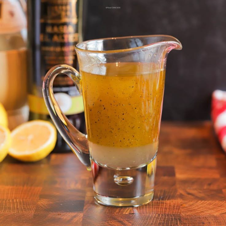 This may contain: a pitcher filled with liquid sitting on top of a wooden table