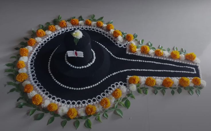 This may contain: a black hat with white and yellow flowers on it is hanging from the wall next to a green leafy plant