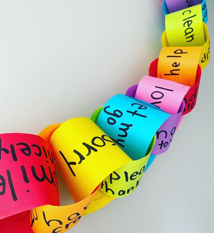 This may contain: colorful paper hearts with words written on them hanging from a white wall in the shape of a heart