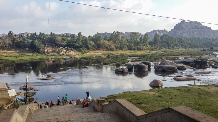 This may contain: several people are standing on the edge of a river