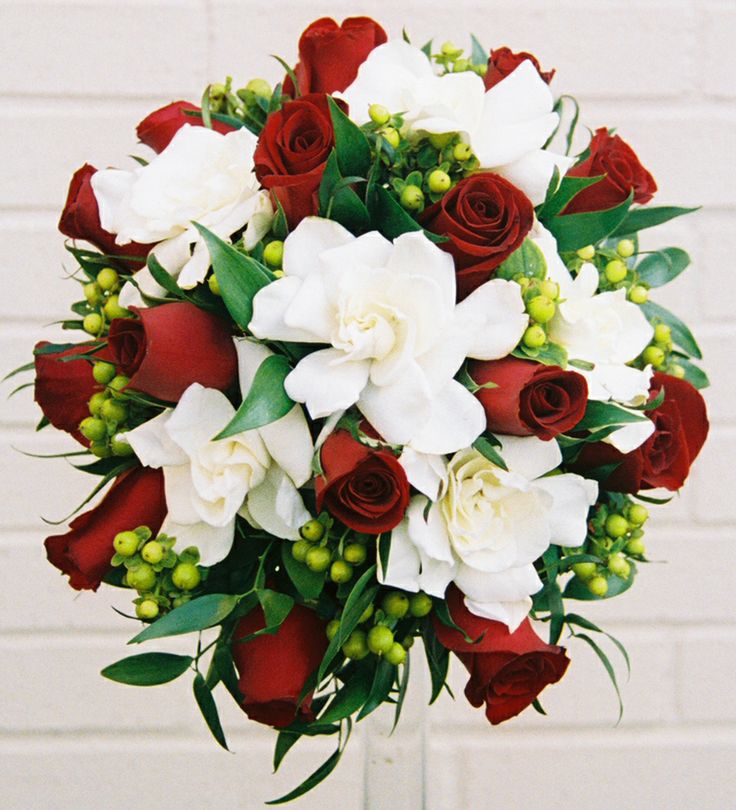 This may contain: a bouquet of white and red flowers in front of a brick wall
