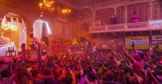 This may contain: people celebrating holi dance in front of a stage with lights and banners on it