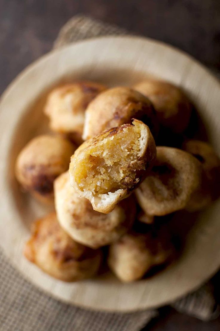This may contain: a white bowl filled with doughnuts on top of a table
