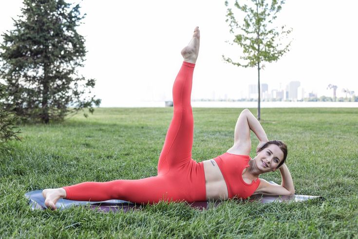 This may contain: a woman in a red outfit is doing exercises on a yoga mat with her legs up