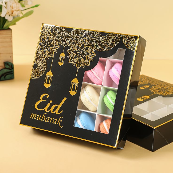 This may contain: two boxes with macaroons in them sitting on a table next to a vase