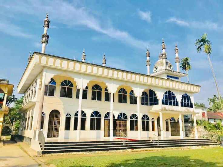 This may contain: a large white building sitting on top of a lush green field