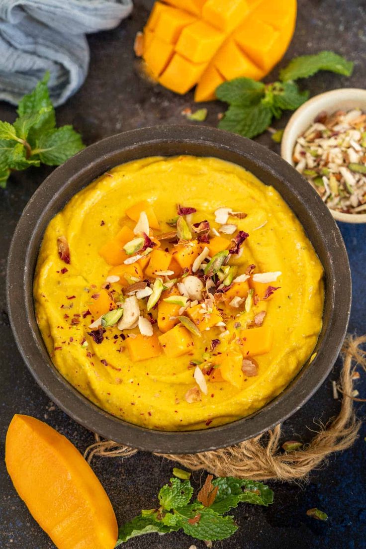 This may contain: a bowl filled with yellow hummus next to some sliced up pumpkins and nuts